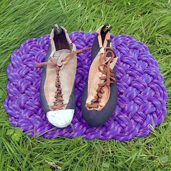 Picture showing an old and worn La Sportiva Mythos climbing shoe, repaired at the toes with climbing tap, together with a brand new one.